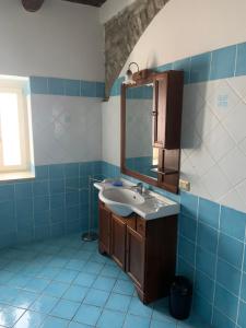 W wyłożonej niebieskimi kafelkami łazience znajduje się umywalka i lustro. w obiekcie B&B Panta Rei w mieście Cicerale