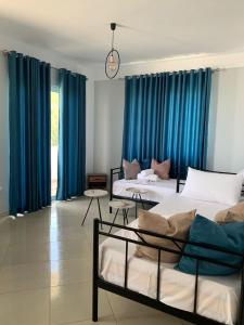 twee bedden in een kamer met blauwe gordijnen bij Mediterranean Apartments in Himare