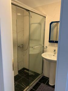 een badkamer met een glazen douche en een wastafel bij Mediterranean Apartments in Himare