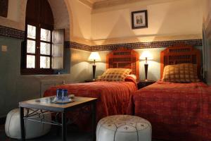 a bedroom with two beds and a table and two lamps at Dar Al Kounouz in Marrakesh