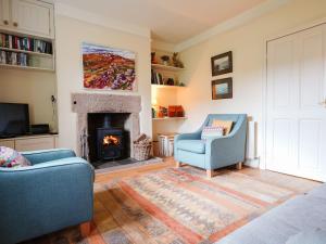 a living room with two chairs and a fireplace at Cloudberry Cottage in Stanton in Peak