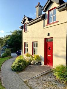 una puerta roja al lado de una casa en 1 Keelkyle Cottage Connemara Letterfrack County Galway en Letterfrack