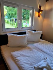 a bed with white sheets and pillows next to a window at Haus DeMa in Walkenried +59 photos