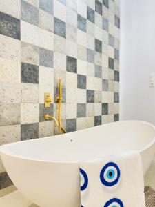 a white bath tub in a bathroom with a tiled wall at Gerani Deluxe Houses in Astypalaia