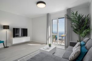 a living room with a couch and a tv at Intelsol Calheta Apartments by An Island Apart in Calheta