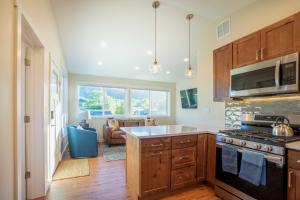 a kitchen with a stove top oven next to a living room at Modern Golden Cottage with Incredible Mountain View! in Golden