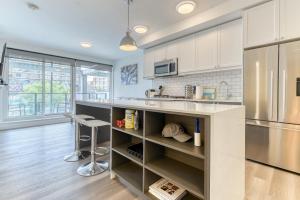 a kitchen with white cabinets and a stainless steel refrigerator at Kensington Suite 2bed & 1bath in Calgary