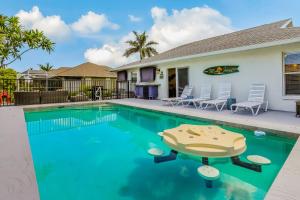 a swimming pool in front of a house at Sun-Drenched Sojourn in Marco Island