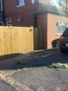 a car parked in a driveway next to a wooden fence at Spacious one bedroom ground floor apartment in Harrogate