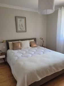 a large white bed in a white bedroom with a window at La Mosloise in Mosles