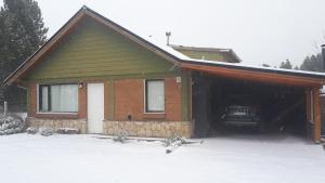 a house with a garage with snow on the ground at Escallonia House in San Martín de los Andes