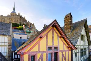 ein gelbes und orangefarbenes Gebäude mit einem Schloss im Hintergrund in der Unterkunft Mercure Mont Saint Michel in Le Mont Saint Michel
