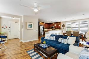 un soggiorno con un divano blu e una cucina di Seacliff Retreat Gorgeous third-floor condo with pool, hot tub, & fitness room - walk to beaches a Oceanside