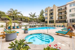 una piscina in un hotel con panchine e palme di Seacliff Retreat Gorgeous third-floor condo with pool, hot tub, & fitness room - walk to beaches a Oceanside