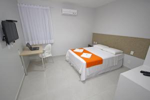 Schlafzimmer mit einem Bett, einem Schreibtisch und einem TV in der Unterkunft Hotel Encantos de Penedo Alagoas in Penedo