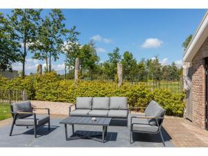 a patio with a couch and two chairs and a table at Very luxurious holiday home in beautiful Zeeland style suitable for 7 people in Vrouwenpolder