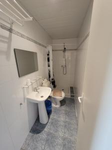 a white bathroom with a toilet and a sink at Hôtel Marquette in Lourdes