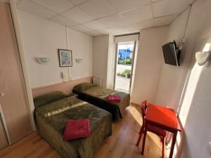 Cette petite chambre comprend 2 lits et une fenêtre. dans l'établissement Hôtel Marquette, à Lourdes