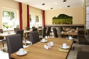 een restaurant met houten tafels, stoelen en ramen bij Hotel garni Grundmühle in Bad Schandau