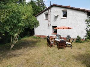 a table with chairs and an umbrella in front of a house at Gemütliches Ferienhaus "An der Schilde" in Renzow in Renzow