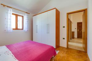 a bedroom with a pink bed and a mirror at Apartments Nives, Artatore in Mali Lošinj