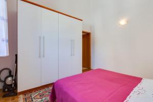 a bedroom with white walls and a bed with a purple blanket at Apartments Nives, Artatore in Mali Lošinj