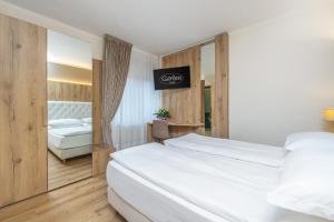 a hotel room with two beds and a mirror at Garden Wellness Hotel S in Andalo