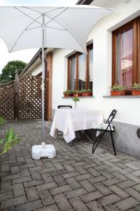 - une table blanche et un parasol sur la terrasse dans l'établissement Holiday home Fattoria Laghetto, à Merate