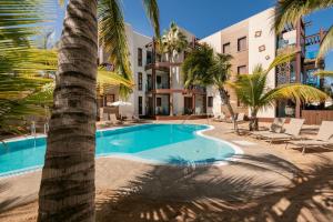uma piscina com uma palmeira em frente a um edifício em Alhambra Boutique Apartments by TAM Resorts em Playa del Inglés