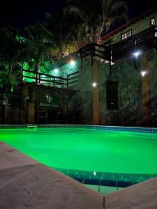 una piscina vacía por la noche con iluminación verde en Buzios Casa 2, en Búzios
