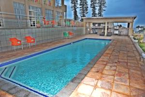 a swimming pool with orange chairs next to a building at The Norwegian Lodge in Umkomaas