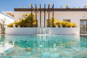 a swimming pool with a fountain in front of a building at Silvi Villas by TAM Resorts in Playa del Ingles