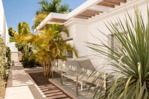 a white house with palm trees in front of it at Aevum Resort in Playa del Ingles