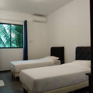2 camas en una habitación con ventana en RIVERSIDE PALM INN SG LEMBING, en Sungai Lembing