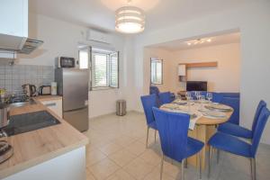 kuchnia i jadalnia ze stołem i niebieskimi krzesłami w obiekcie Apartment S and E w mieście Kali