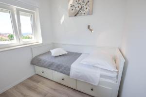 łóżko w białym pokoju z 2 oknami w obiekcie Apartment S and E w mieście Kali