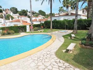 a swimming pool in a yard with trees and houses at Coastal Comfort with Pool in Denia