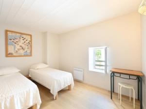 a bedroom with two beds and a table and a window at Maison Rénovée avec Jacuzzi et Cuisine d'Été au Centre du Village - FR-1-434-97 in La Couarde-sur-Mer