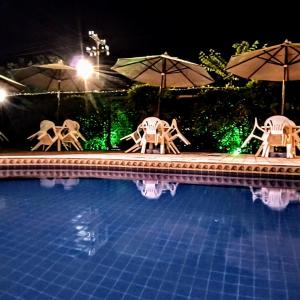 two chairs and umbrellas next to a swimming pool at night at Pousada Marahú in Porto De Galinhas