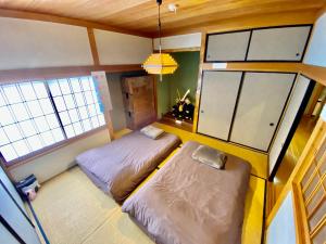2 Betten in einem kleinen Zimmer mit Fenstern in der Unterkunft 貸切御宿Villa EL 5 Nikko Kinugawa Area in Nikko