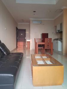 ein Wohnzimmer mit einer schwarzen Couch und einem Tisch in der Unterkunft lovely 1 bedroom apartment the bellezza permata in Jakarta