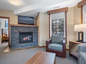 a living room with a fireplace with a tv and a chair at Sunny Tranquil Woods Turret in Falcon Crest Lodge in Canmore