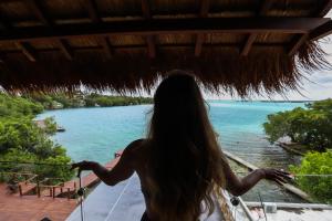 a woman standing on a balcony looking out at the ocean at Hotel Amainah Bacalar Adults Only in Bacalar