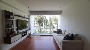 sala de estar con sofá blanco y ventana grande en Apartment 4 Rent - Av San Borja Norte Cdra 8 en Lima