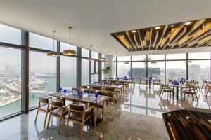 a restaurant with tables and chairs in a room with windows at Hotel Adela in Busan