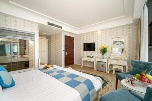 een hotelkamer met een groot bed en een bank bij Royal Beach Hotel by THG in Da Nang