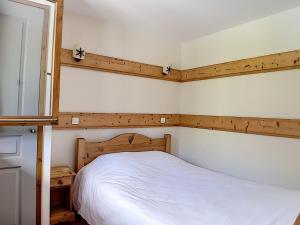 Schlafzimmer mit einem weißen Bett mit einem Kopfteil aus Holz in der Unterkunft Appartement Les Menuires, 3 pièces, 6 personnes - FR-1-344-758 in Levassaix