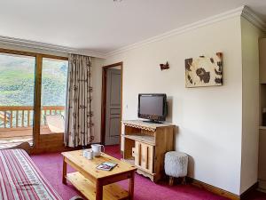 ein Wohnzimmer mit einem TV und einem Holztisch in der Unterkunft Appartement Les Menuires, 3 pièces, 6 personnes - FR-1-344-758 in Levassaix