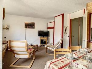 ein Wohnzimmer mit zwei Stühlen, einem Tisch und einem Fernseher in der Unterkunft Appartement spacieux 6 pers · Proche des pistes · Parking inclus - FR-1-344-750 in Les Menuires
