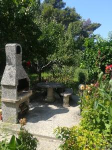 un banco de piedra y una mesa en un jardín en Alemka, en Banjol